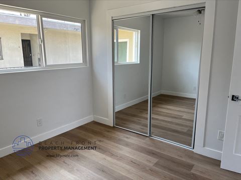 a bedroom with mirrored closet doors and a hard wood floor